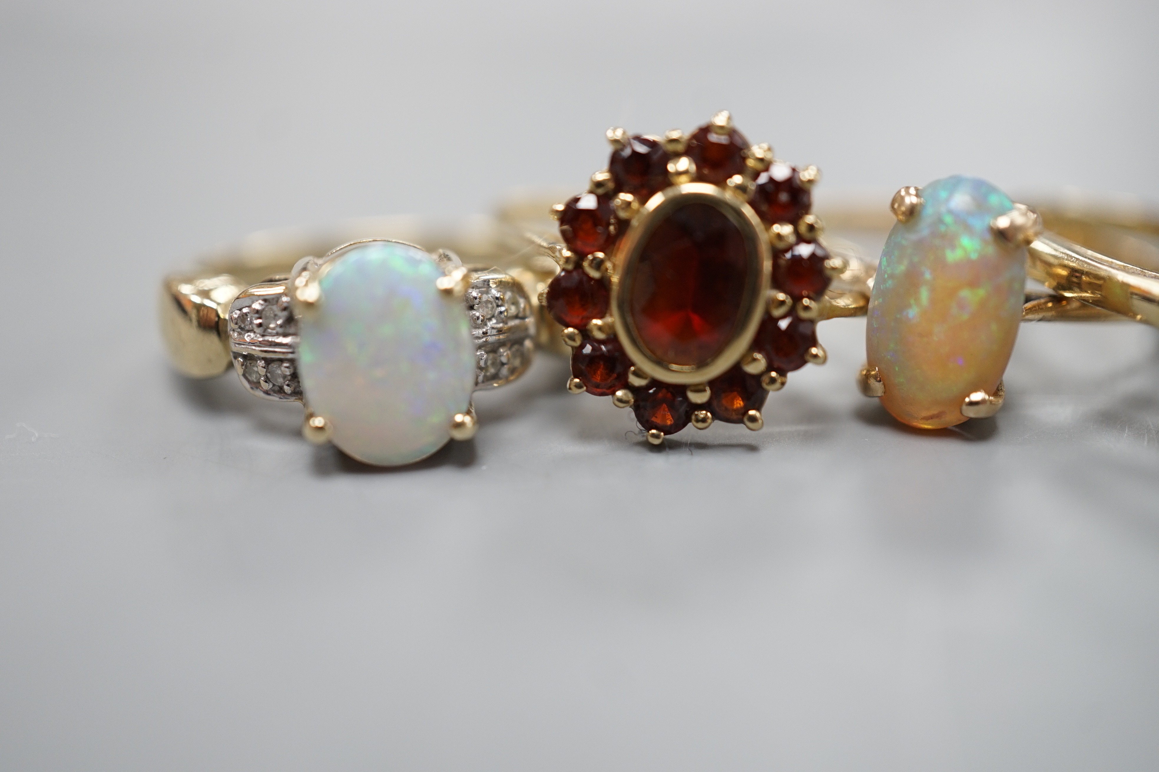 Five assorted modern 9ct gold and gem set dress rings, including white opal and diamond chip cluster, white opal cluster and garnet cluster